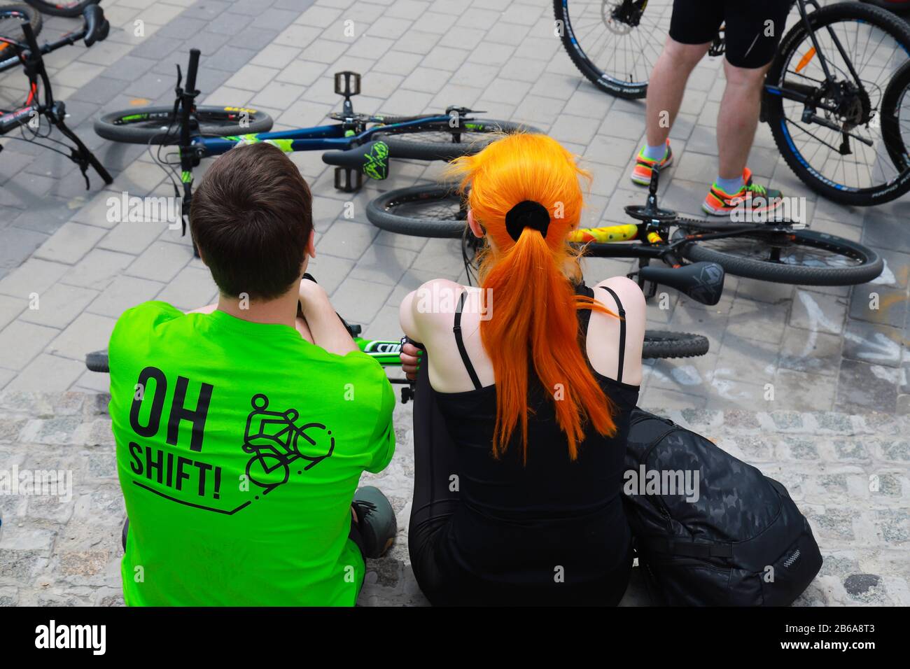 Giovane ragazzo e ragazza sono seduti vicino a biciclette in strada. Ciclisti durante un evento sportivo ciclistico. Sport di città, città di Dnipro, Ucraina Foto Stock