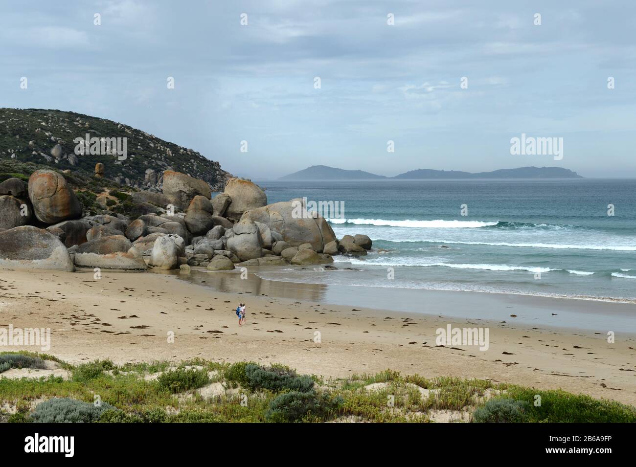 Coppia sulla spiaggia a Whisky Beach. Massicci massi di granito adornano la costa come sculture naturali Foto Stock