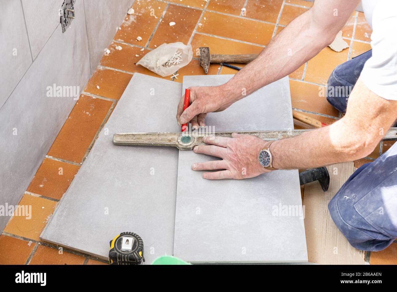 L'installatore misure piastrella prima del taglio Foto Stock