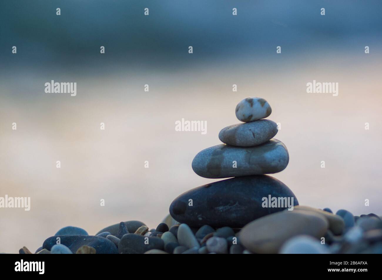 Piramide piegata Zen pietre ghiaia sul mare spiaggia al tramonto Foto Stock