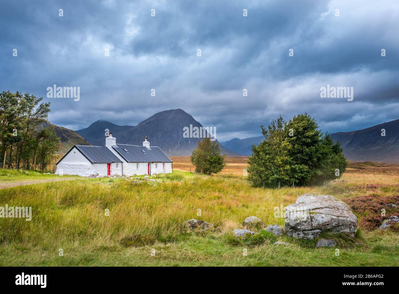 Blackrock Cottage sotto i cieli tempestosi con le montagne sullo sfondo. Glencoe, Scottish Highlands, Regno Unito Foto Stock