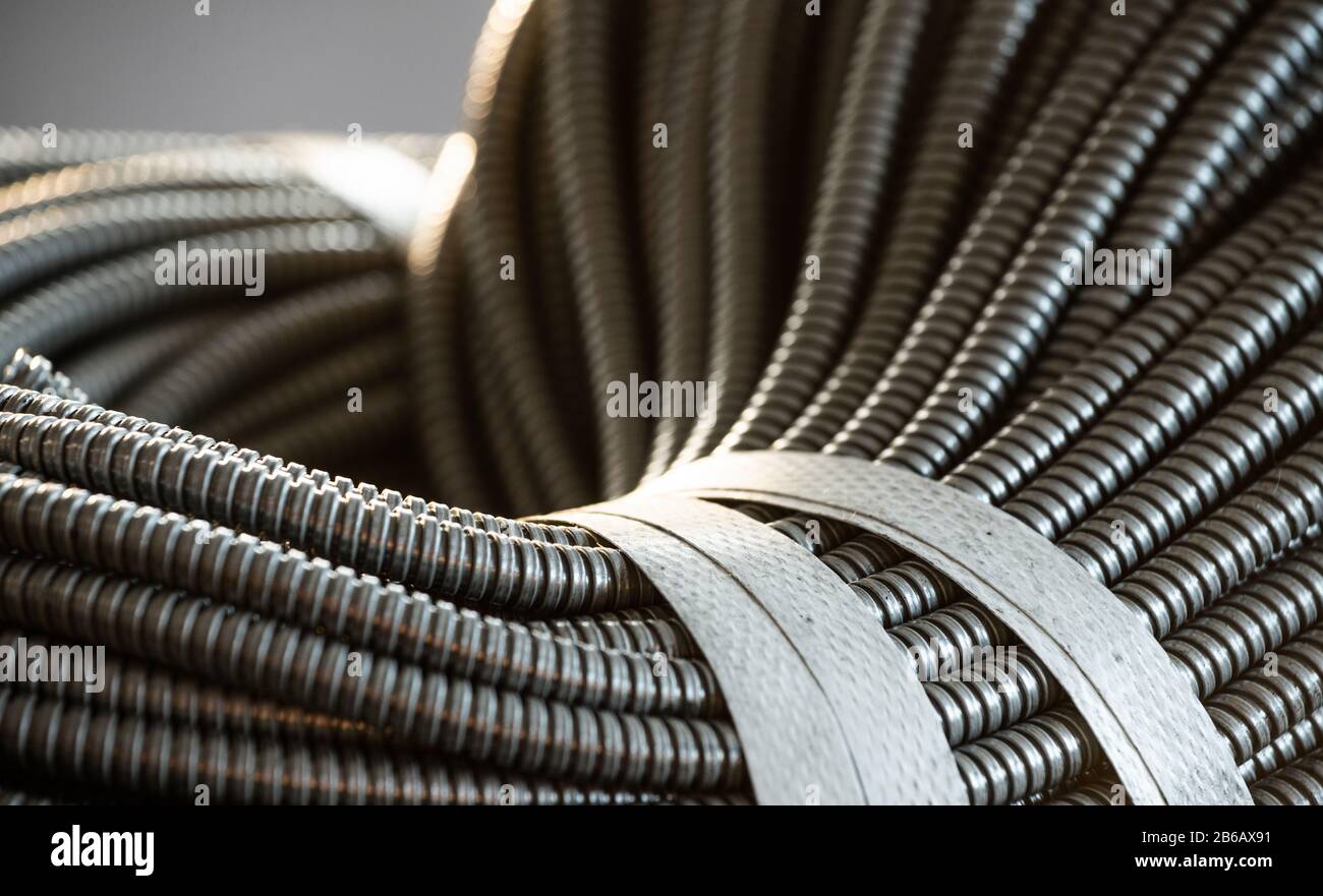 Primo piano di un enorme gruppo di tubi flessibili in metallo interconnessi in una fabbrica o in un impianto. Il concetto di moderna tecnologia elettronica E IT. Copyspace Foto Stock