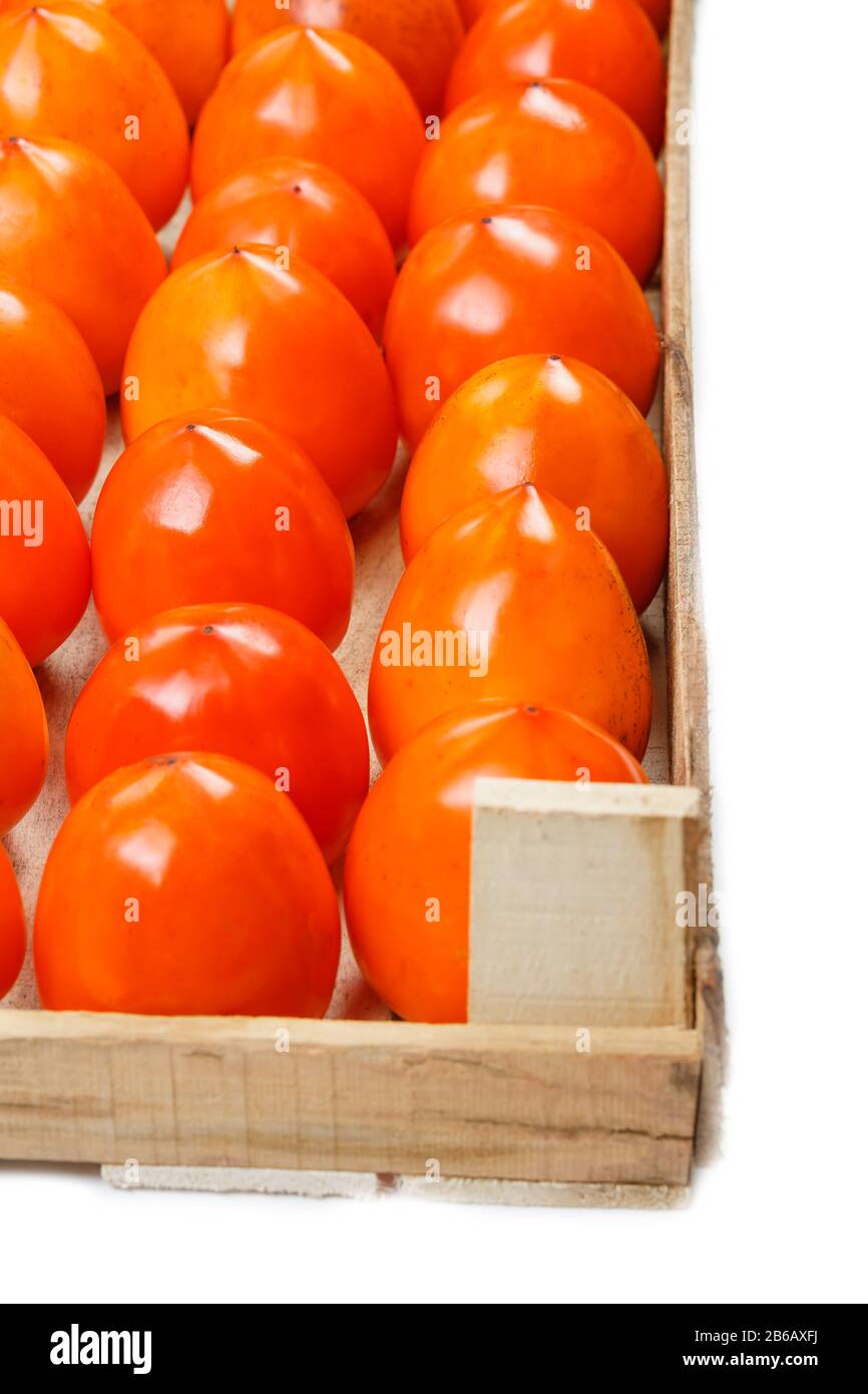 Frutta di Persimmon nella scatola di legno isolato su bianco. Tracciato di ritaglio incluso. Succosa persimmon maturo in una grande scatola di legno su sfondo bianco. Metà WO Foto Stock