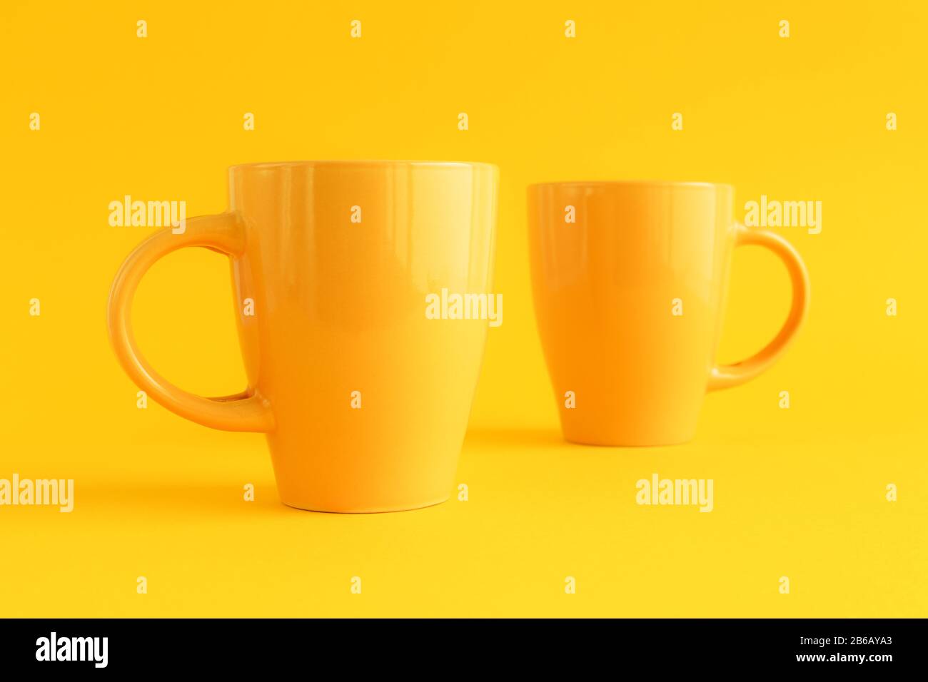 Due tazze di caffè giallo su sfondo giallo, pausa caffè e concetto di dipendenza dalla caffeina Foto Stock
