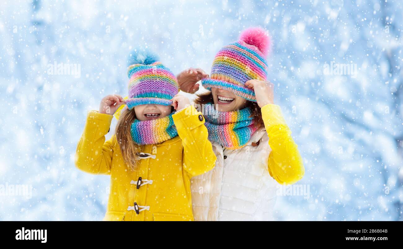 La madre e il bambino in maglia inverno cappelli giocare nella neve sulla famiglia vacanze di Natale. Fatte a mano cappello di lana e sciarpa per mamma e bambino. Maglia per bambini. Kni Foto Stock