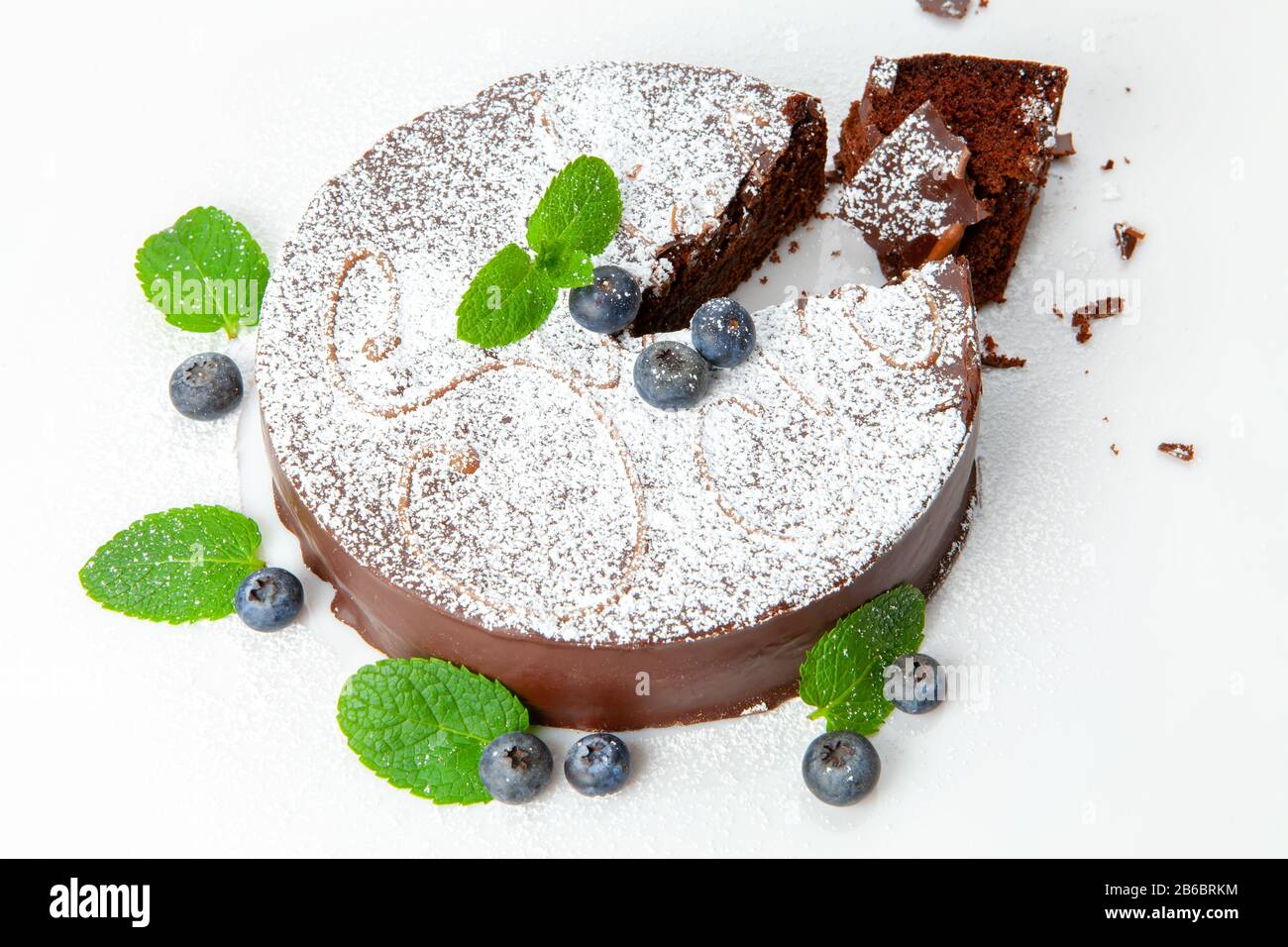 Torta al cioccolato decorata con zucchero bianco polvere mirtillo e foglie di menta. Foto Stock