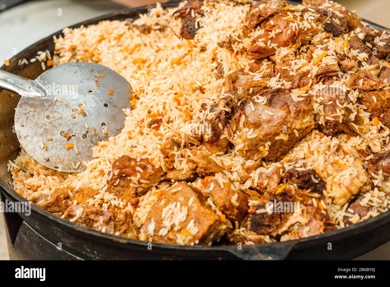 Gustosa Uzbek pilaf in un calderone sul fuoco in aria aperta a street food festival Foto Stock