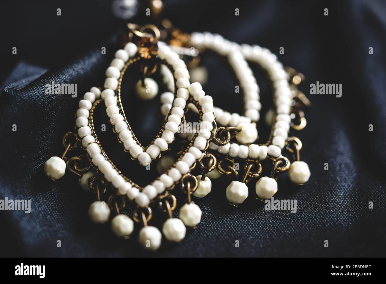 Primo piano di un paio di orecchini in stile etnico con perle bianche Foto Stock