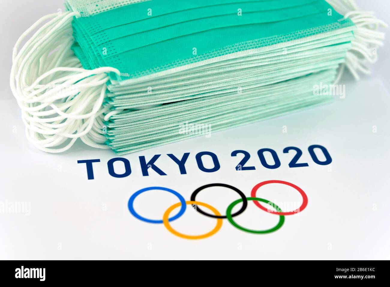 Logo Tokyo 2020 stampato su carta e pile di maschere facciali protettive contro i virus. Concetto. Messa a fuoco selettiva. Foto Stock