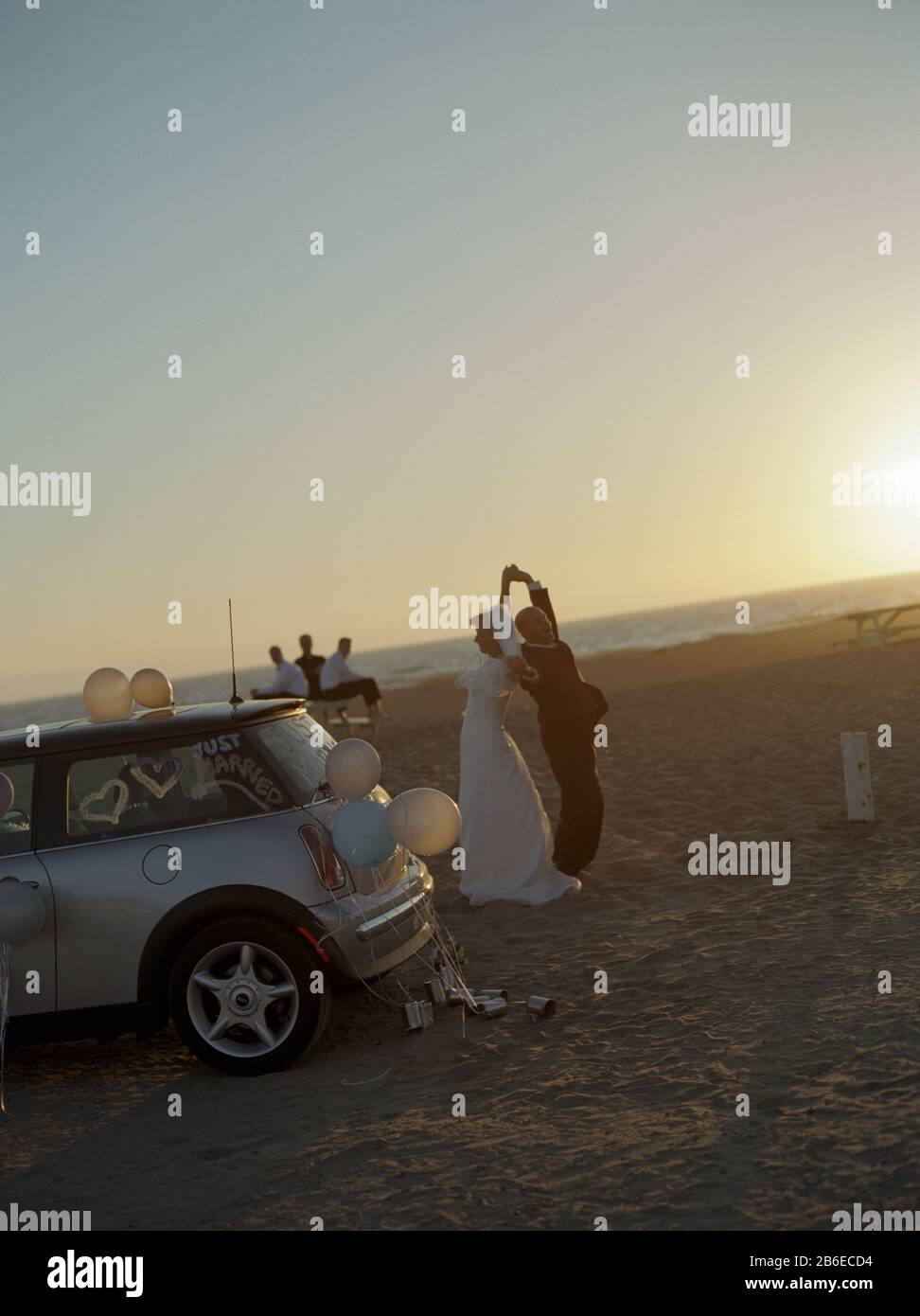 Sposa e Sposo che danzano insieme su una spiaggia di sabbia al tramonto. Foto Stock