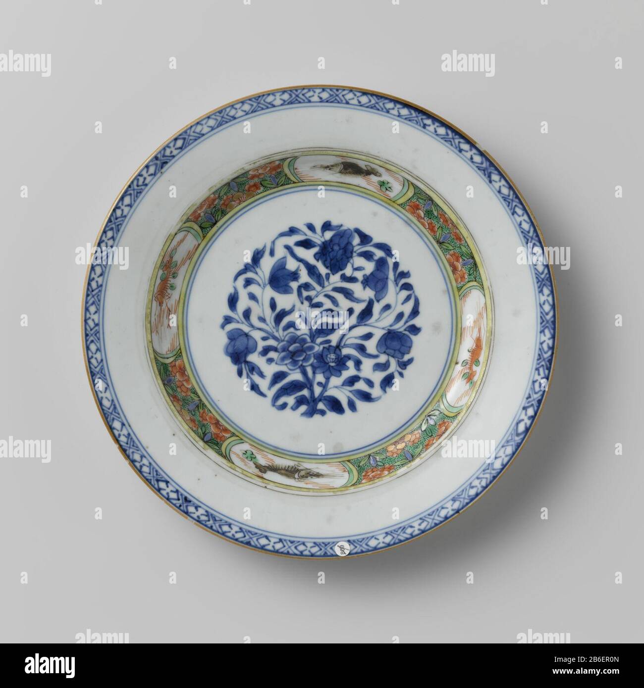 Piatto con rosetta di fiori e pesce in cartoces Bord van porselein, beschilderd in onderglazuur blauw en op het glazuur blauw, rood, groen, zwart en goud. Op het plat een bloemrozet met lotus, pioen en granaatappel; de wand in famille verte email met kreeften en vissen in cartocks afgewisseld met bloemen en bladeen tegen een zwart-gestippelde groene achtergrond; de rand met een band servetwerk. Famille verte. Produttore : pottenbakker: AnoniemPlaats fabbricante: China Dating: CA. 1725 - ca. 1749School / stijl: qing-dynasie (1644-1912) / Yongzheng-periode (1723-1735) / Qianlong-periode ( Foto Stock