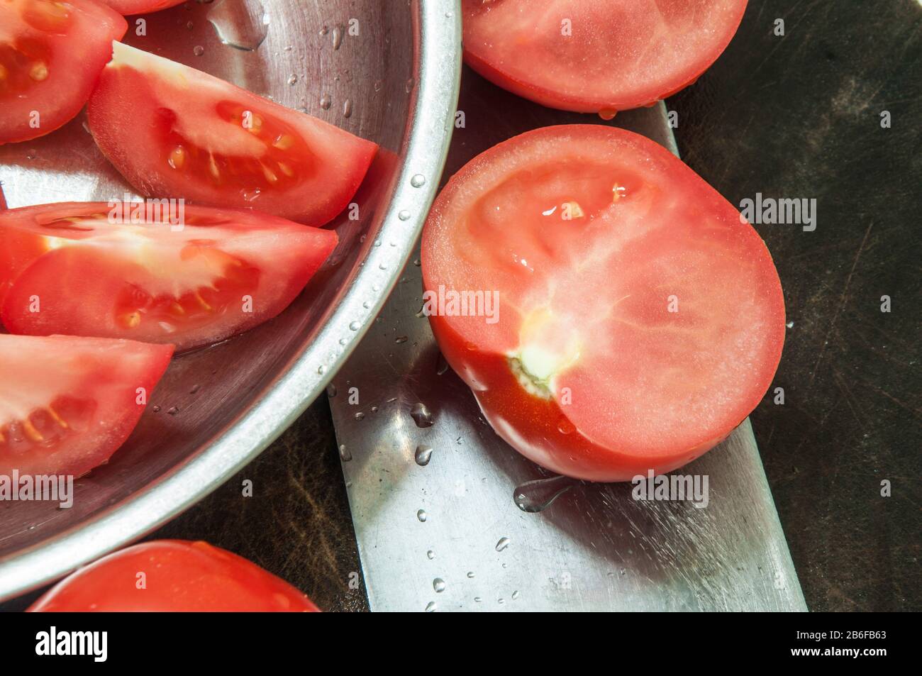 Cibo sfondo. Coltello da cucina con tomatos sul blocco di triturazione. Foto Stock