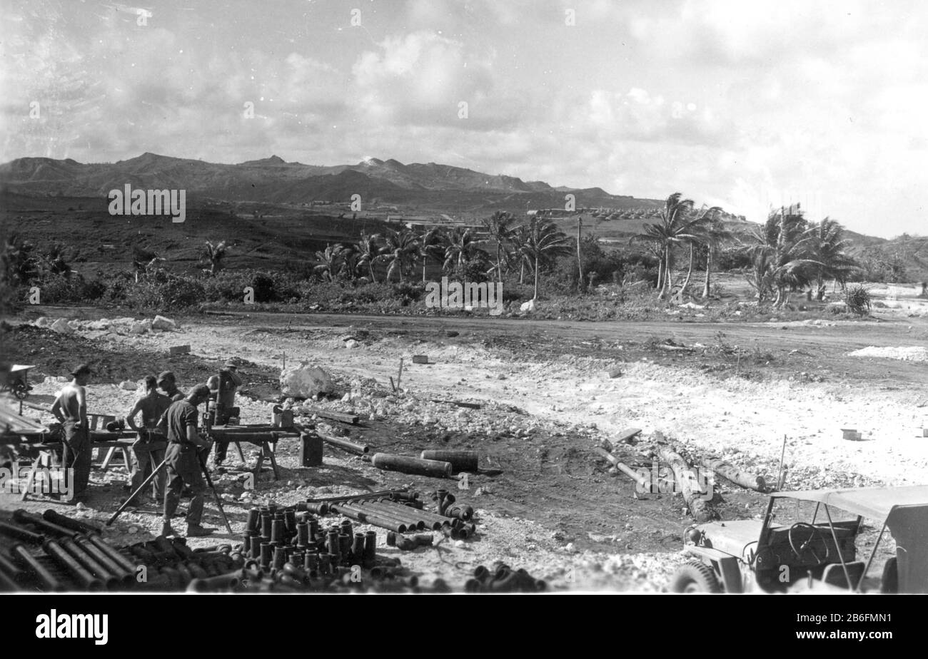Seabees su Guam, n. 1 - caduta di 1944, taglio, preparazione tubi fognari da posare lungo la strada sterrata molto ruvida e rocciosa. Un serbatoio di propano è a terra, benzina può alla sua sinistra. Jeep in basso a destra. In lontananza si trova un campo di tende di fronte alle montagne. Questi Seabee stanno iniziando la costruzione di strade e edifici per gli edifici degli ufficiali CINCPAC. Per vedere le mie immagini d'epoca correlate, Cerca: Prestor vintage WW II Foto Stock