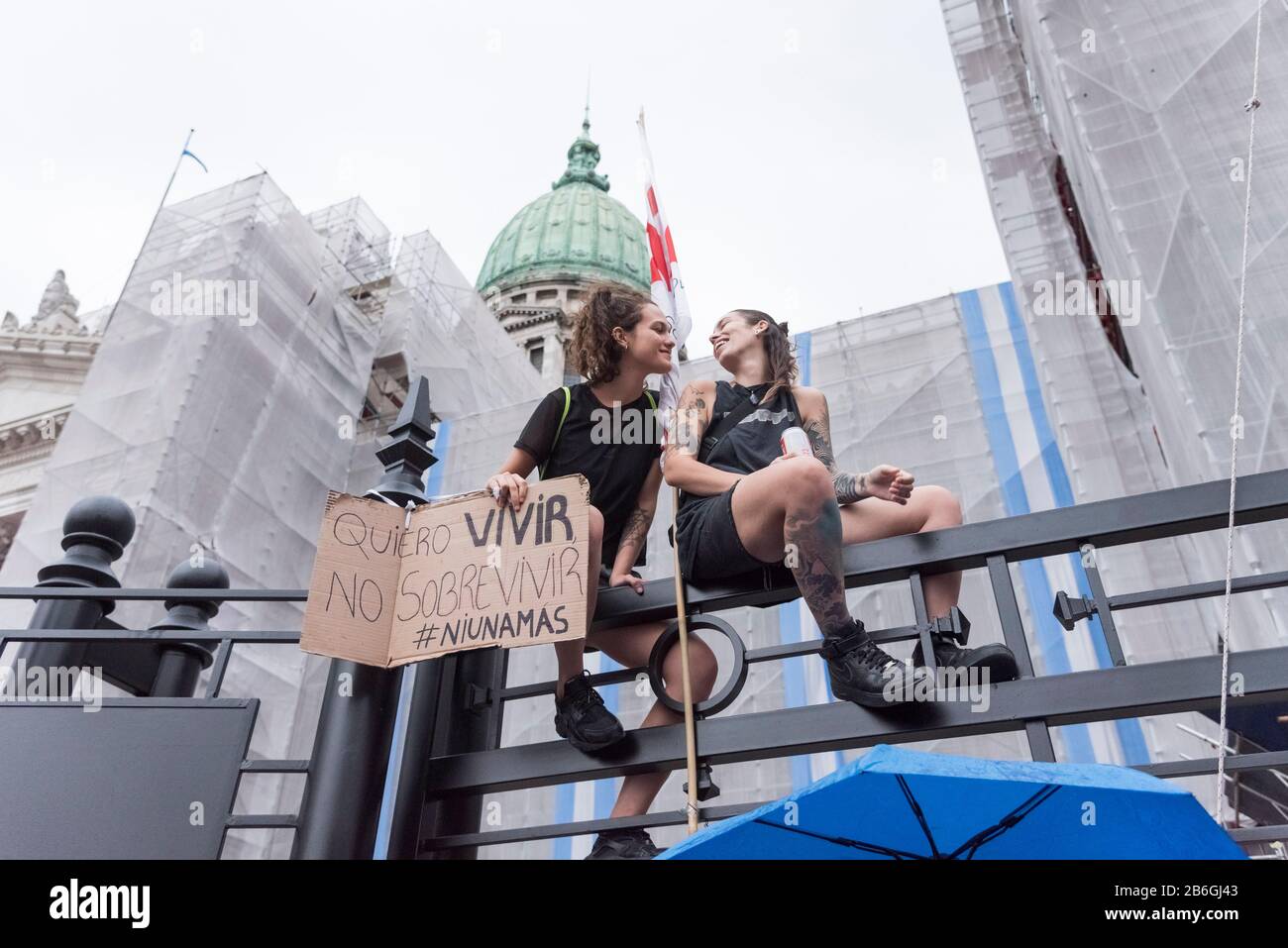 Caba, Buenos Aires / Argentina; 9 marzo 2020: Giornata internazionale delle donne. Le giovani donne si accoppiano in cima ad una recinzione, davanti al Congresso Nazionale. Foto Stock