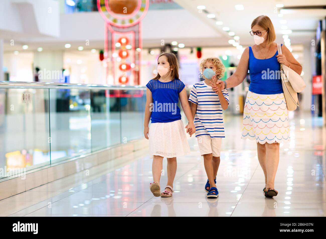 La famiglia indossa la maschera facciale nel centro commerciale in Asia. Madre e bambini indossano facemask durante il coronavirus e l'epidemia di influenza in Cina. Virus e malattia p Foto Stock