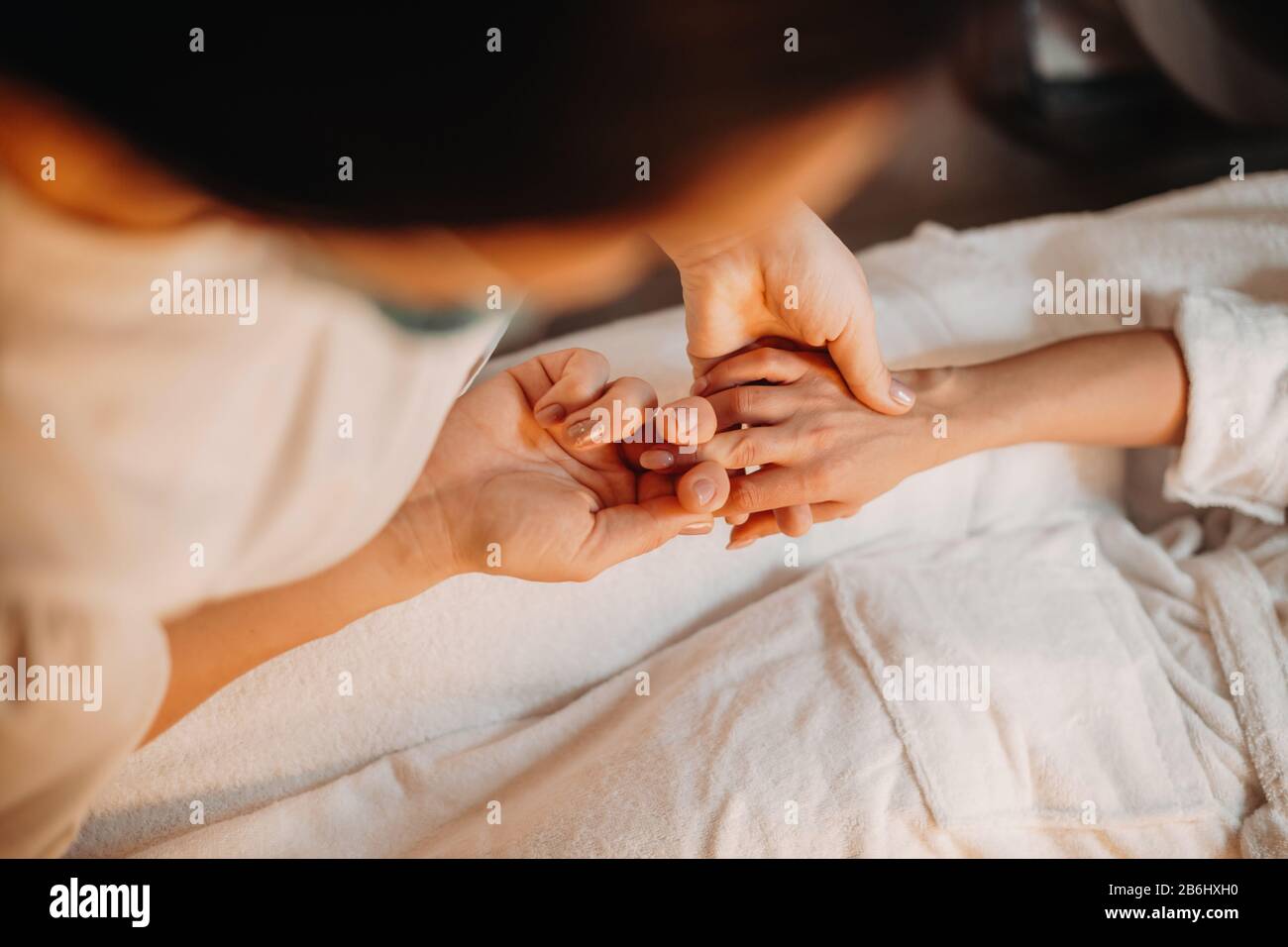 Professionista caucasico spa lavoratore è massaggiante le dita della mano del cliente mentre è sdraiata sul divano Foto Stock