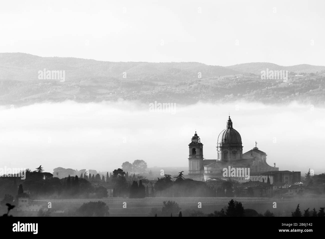 Vista surreale della chiesa papale di Santa Maria degli Angeli (Assisi) sullo sfondo della nebbia Foto Stock