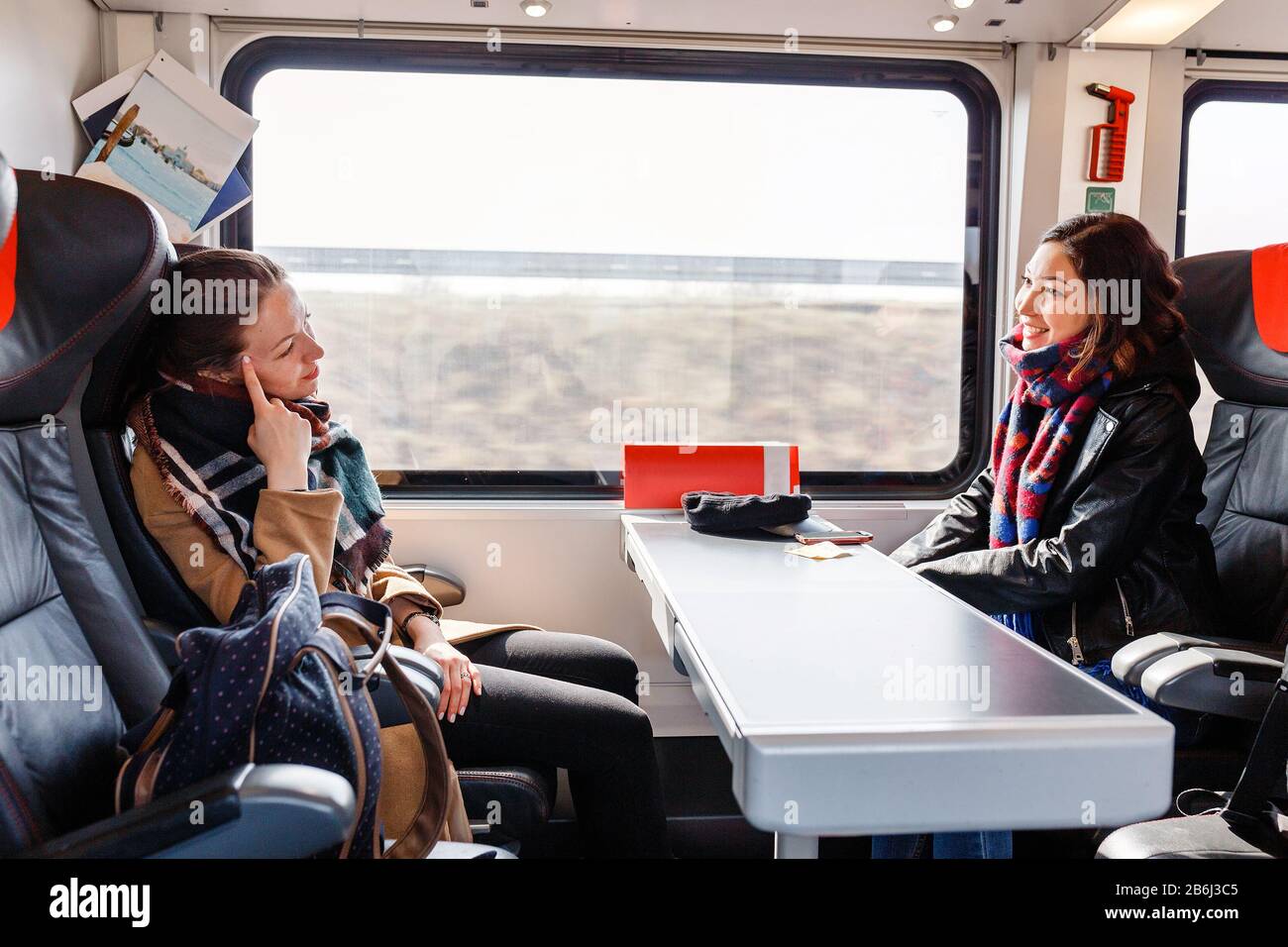 Due donne amici parla e ridere durante il viaggio in treno Foto Stock