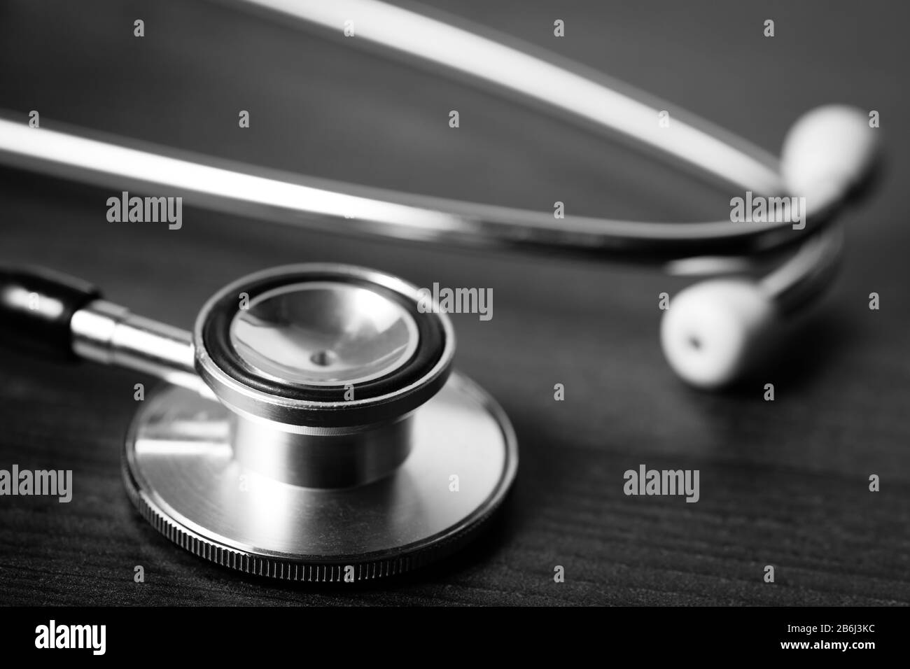 Primo piano dello stetoscopio di un medico seduto su un tavolo di legno scuro. Concetto di salute e benessere. Foto Stock