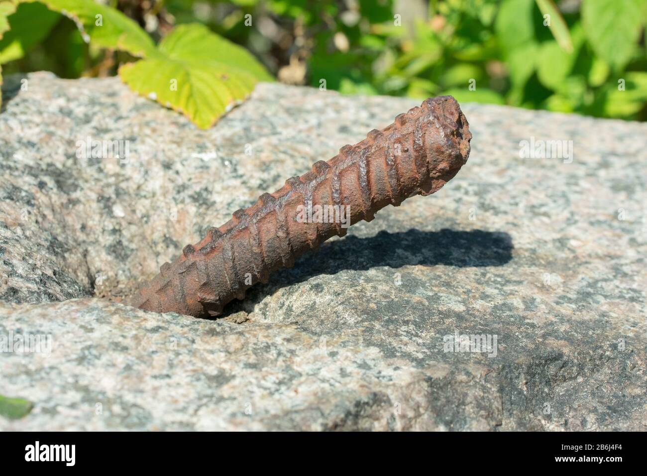 L'estremità di una barra di acciaio arrugginita sporge da una lastra di cemento Foto Stock