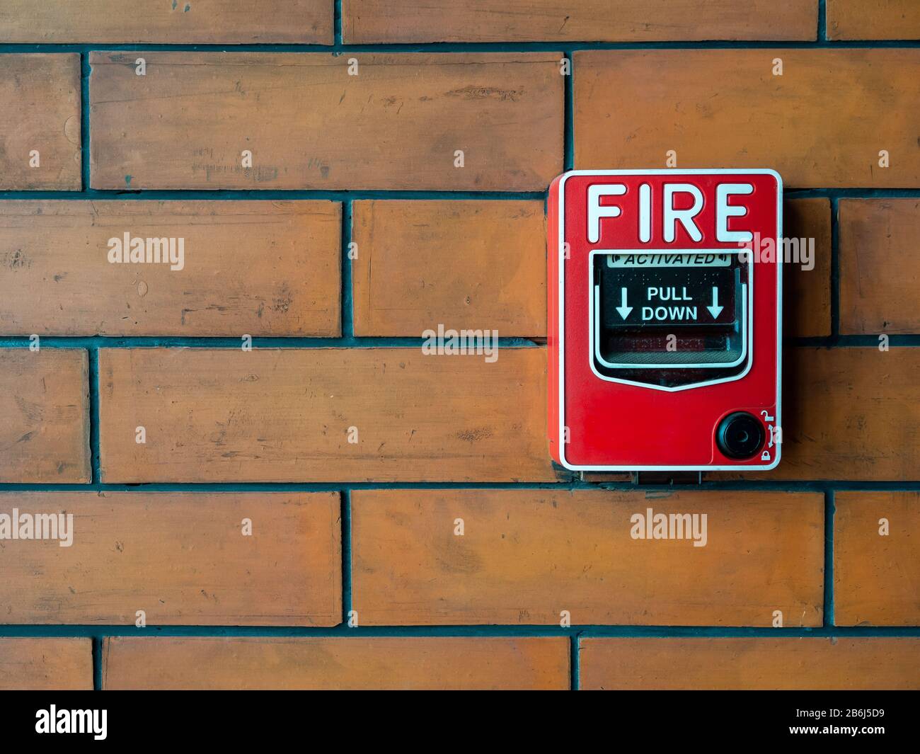 Sistema di sicurezza con allarme antincendio manuale rosso. Postazione pull o call point, attivazione manuale allarme incendio su sfondo muro in mattoni con spazio di copia. Foto Stock