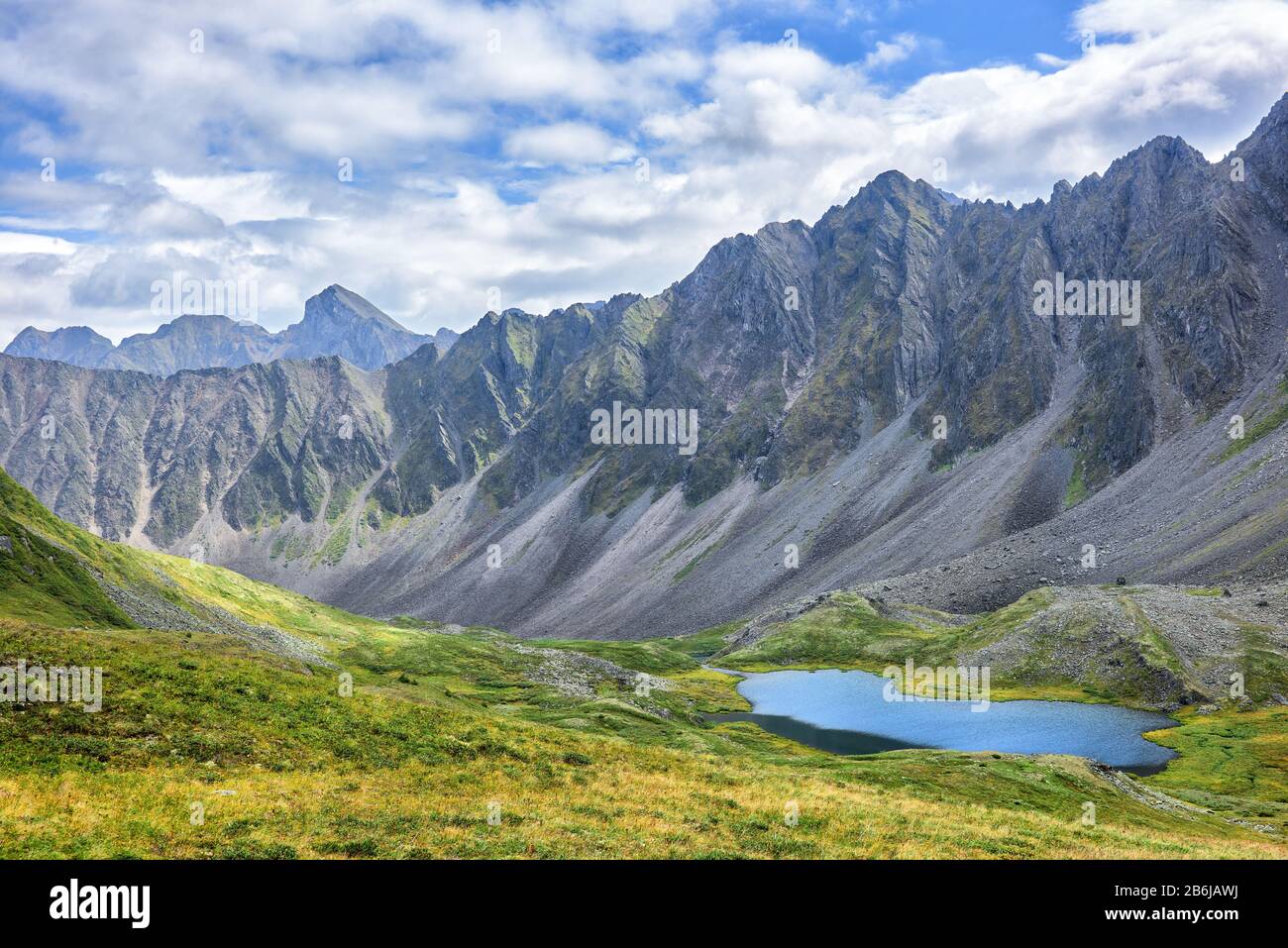 Tundra alpina siberiana sullo sfondo della catena montuosa. Un caratteristico paesaggio alpino con vegetazione scarsa nella Siberia orientale. Valle di valle Foto Stock