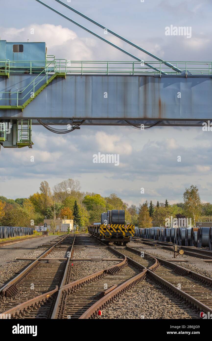 Andernach, Renania Palatinato, Germania - 25 ottobre 2019: Un grande ponte di gru sopra i binari ferroviari e i woggons con spirali in acciaio 4 Foto Stock