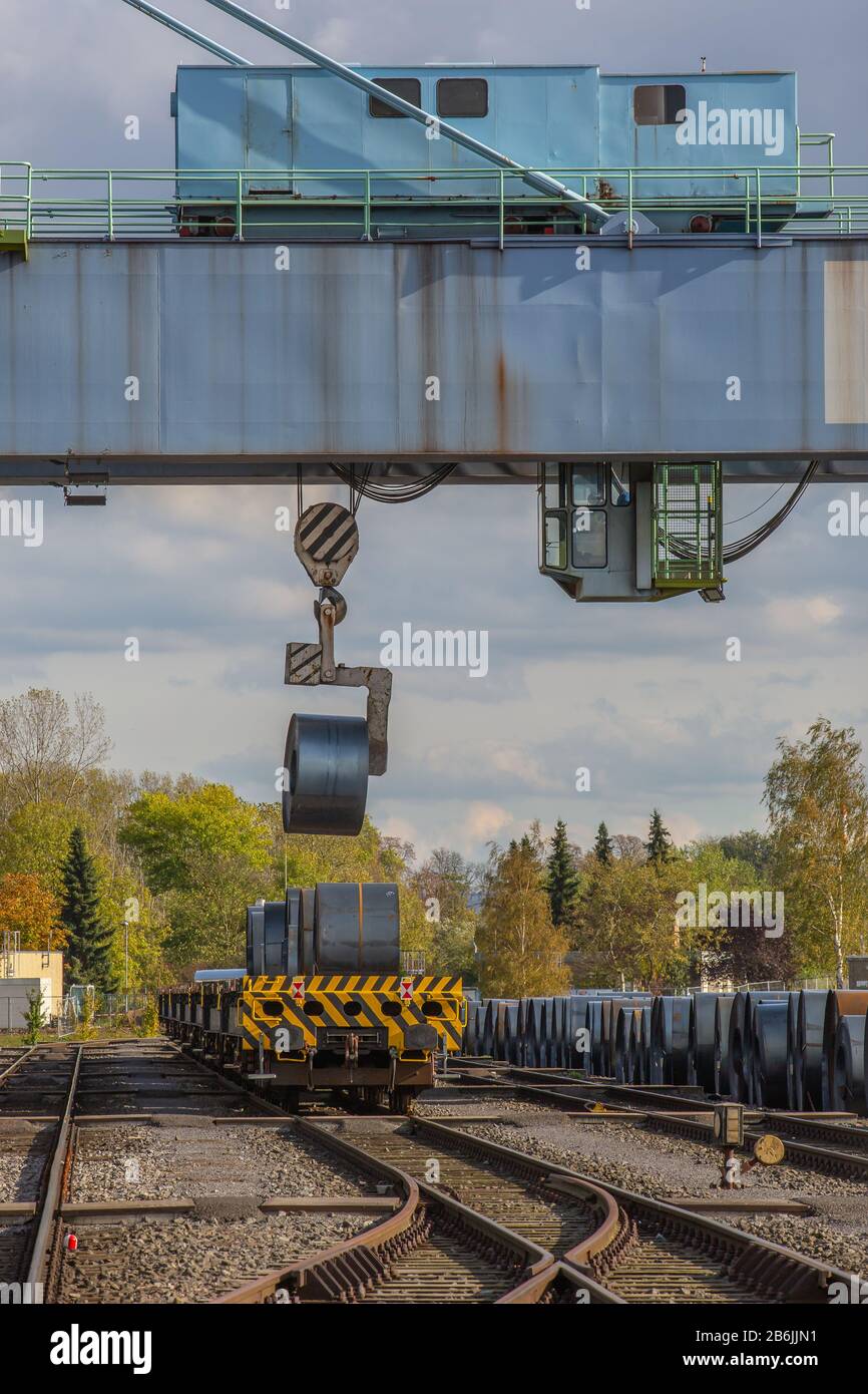 Andernach, Renania Palatinato, Germania - 25 ottobre 2019: Un grande ponte di gru ha sollevato una bobina di metallo per caricarla su un carro Foto Stock