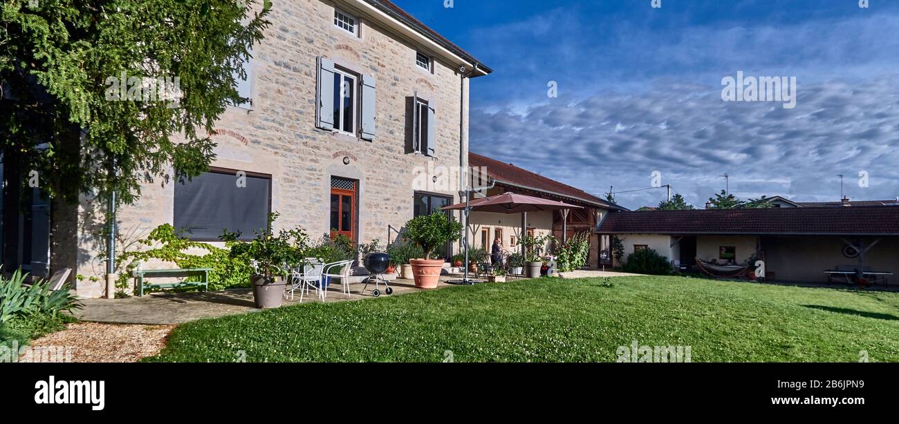 Francia, Bourg-en-Bresse, dipartimento Ain, villaggio Malafretaz, il cortile interno della mia casa di campagna con la sua porta e le persiane e la sua cucina all'aperto. Atmosfera calda e accogliente di questi due spazi abitativi. Foto Stock
