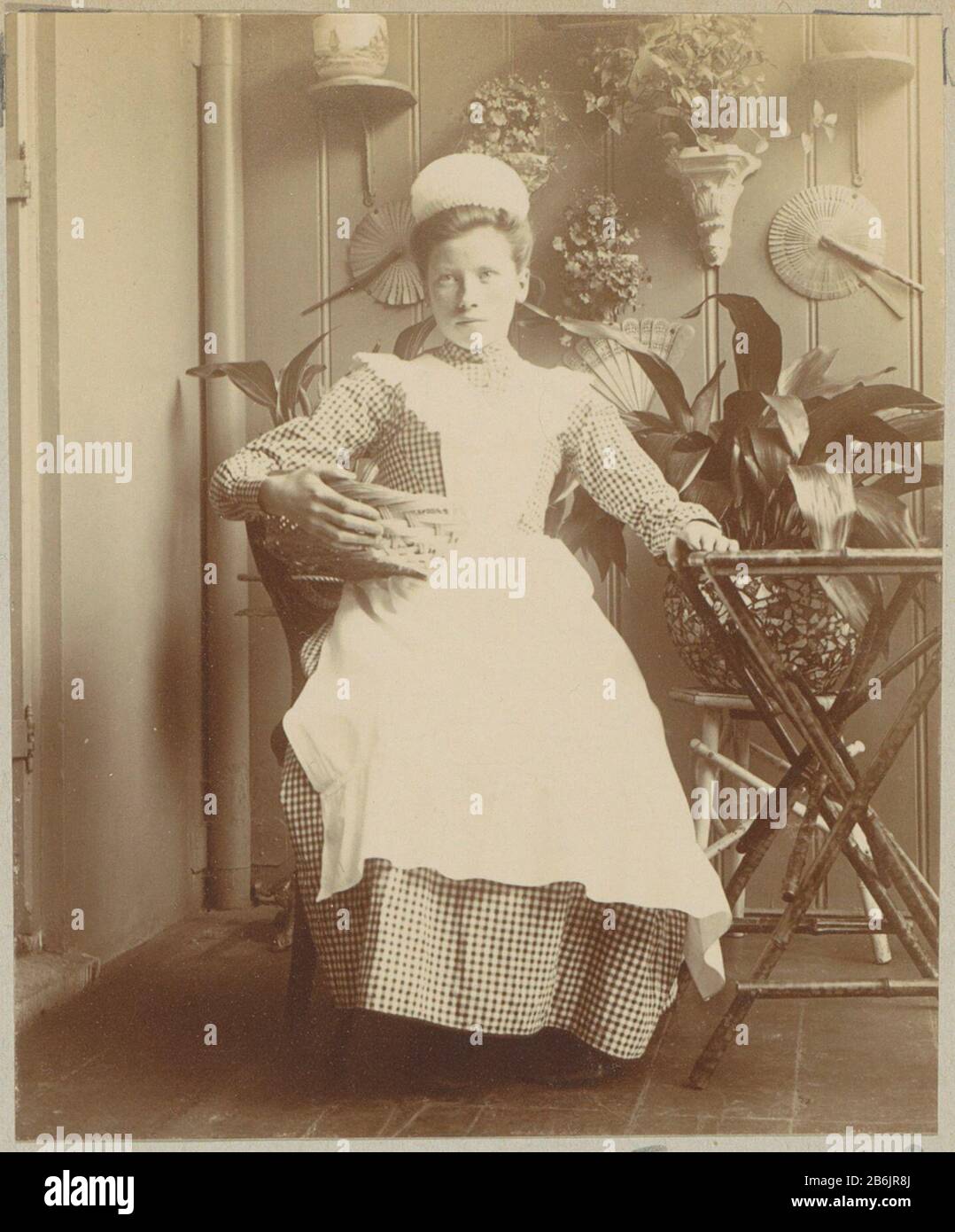 Cameriera seduta in serra con un cesto sul braccio Onderdeel van Familiealbum incontrato on der meer foto van Wijnhandel Kraaij & Co. Bordeaux-Amsterdam. Produttore : fotografaf: Anoniem Dating: CA. 1900 - ca. 1910 kenmerken Fisico: Daglichtpapierafdruk Materiale: Fotopapier Techniek: Daglichtpapierafdruk dimensioni: H 81 mm × b 66 mm Oggetto: Cameriera, cucina servo Foto Stock