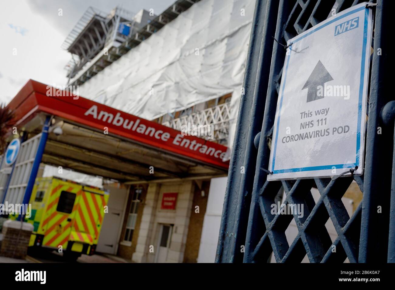 Un cartello NHS punta verso un pod per test Coronavirus, mentre un'ambulanza arriva al DIPARTIMENTO A&e del Kings College Hospital di Camberwell, a sud di Londra, il 11th marzo 2020, a Londra, Inghilterra. Foto Stock