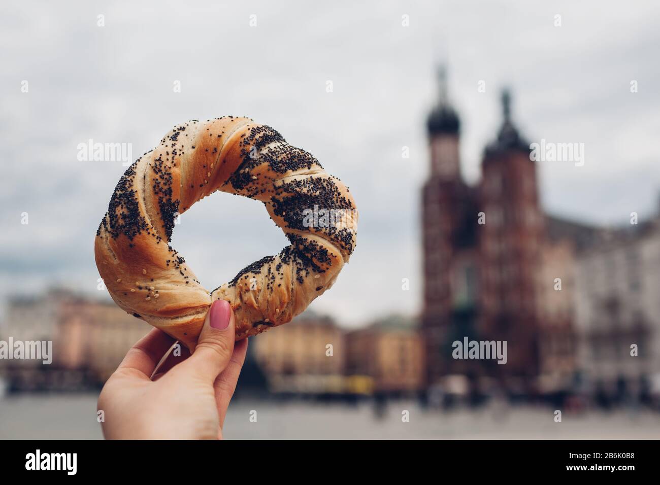 I turisti che tengono il bagel obwarzanek tradizionale spuntino della cucina  polacca sulla piazza del mercato a Cracovia. Viaggi In Europa Foto stock -  Alamy