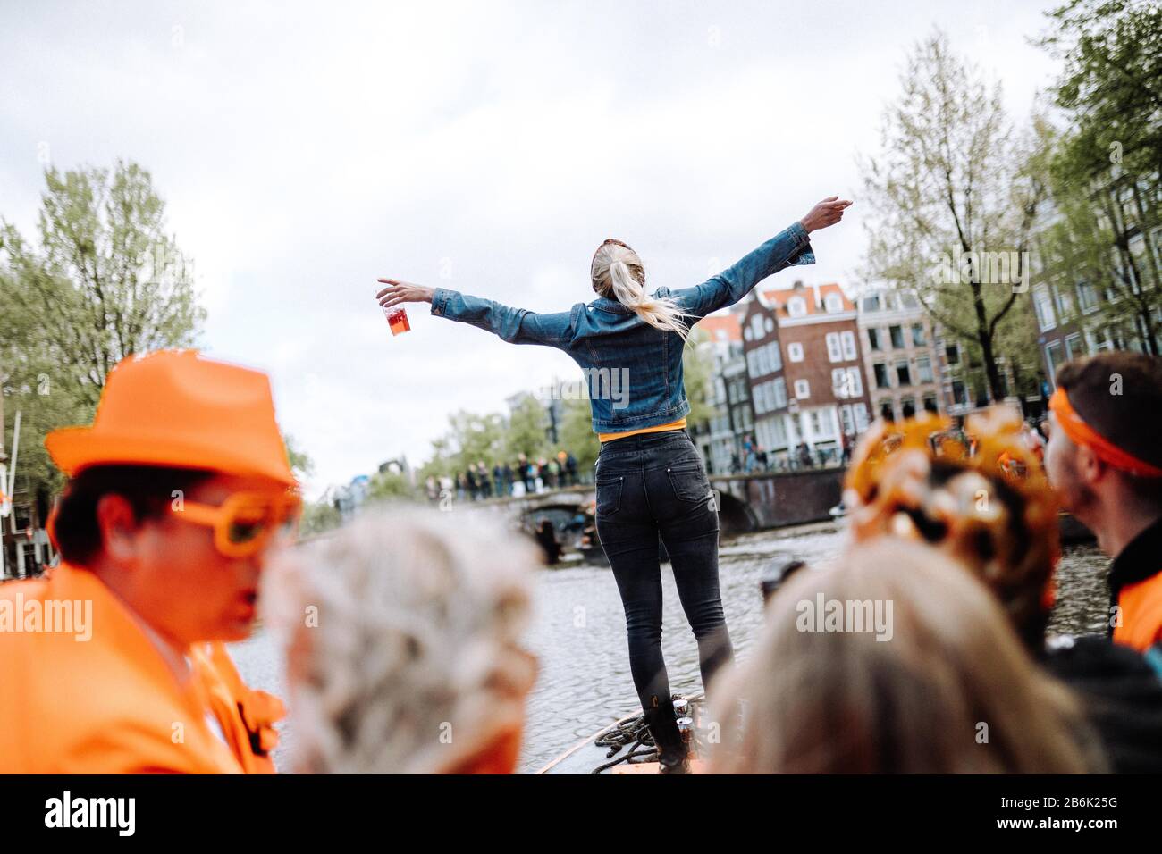 I festaioli arancioni si riversano sulle strade e sui canali di Amsterdam per celebrare il compleanno del re a Koningsdag. Foto Stock