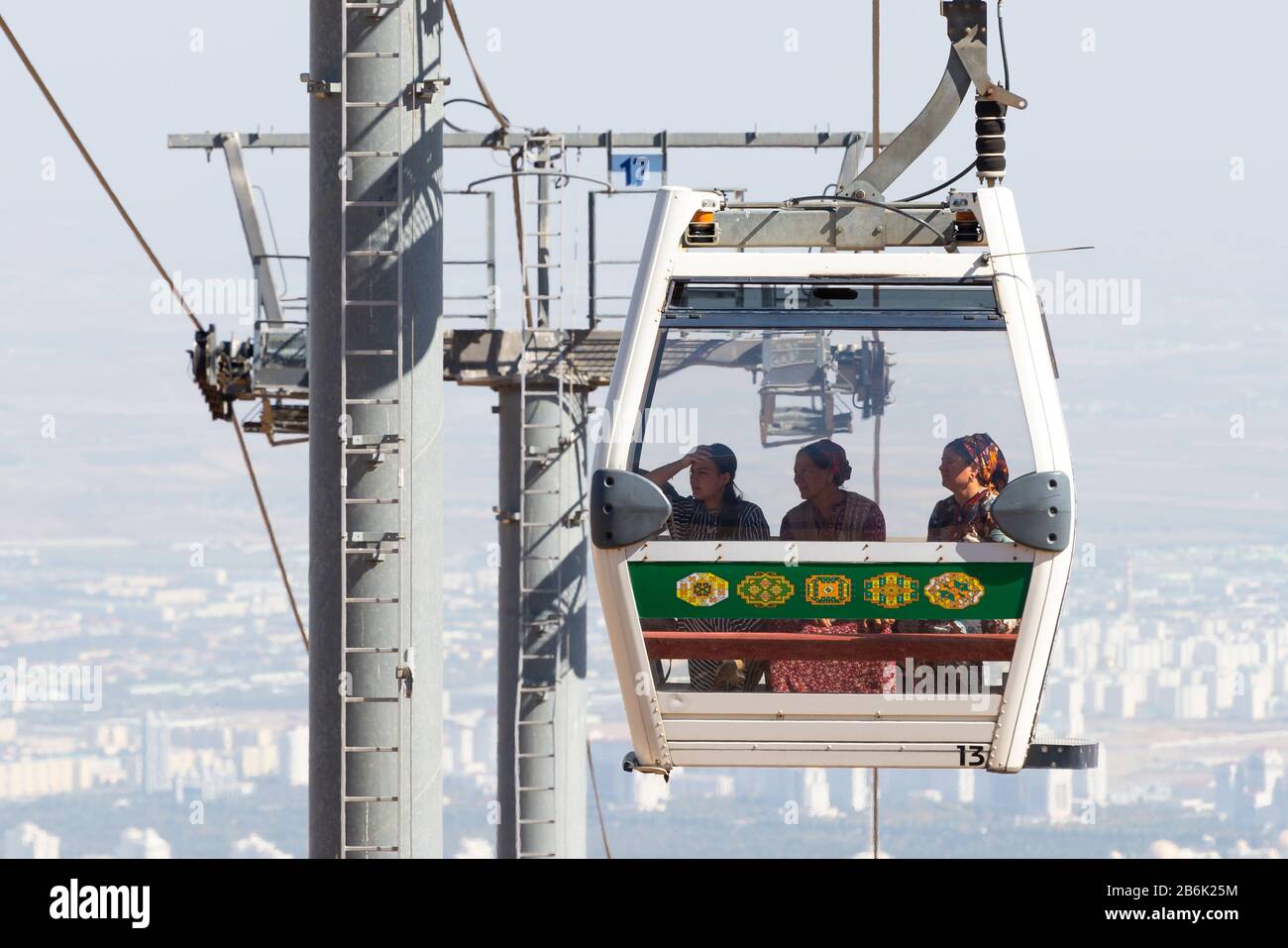Cabinovia aerea ad Ashgabat, Turkmenistan, con tre donne turkmeno locali che indossano abiti nazionali verdi tradizionali e sciarpa a bordo del carro. Foto Stock