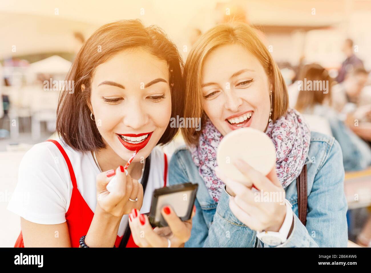 Due ragazze ragazza messo sul trucco, rossetto e sguardo nello specchio. Il concetto di cosmesi e rapporti di stile di vita Foto Stock