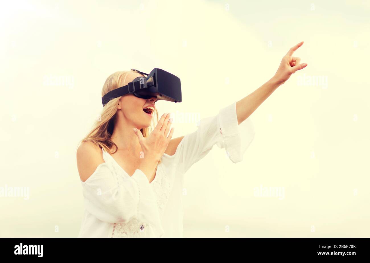 realtà aumentata, gaming, vacanze estive, tecnologia e concetto di persone - stupita giovane donna con auricolare per realtà virtuale o occhiali 3d punta fin Foto Stock