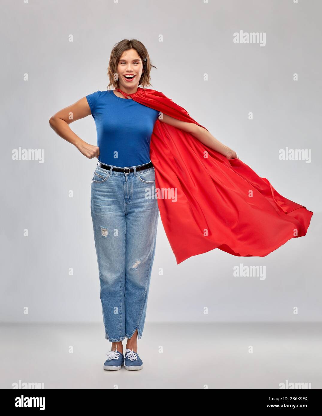 concetto di potere e di gente delle donne - donna felice in capo supereroe rosso su sfondo grigio Foto Stock