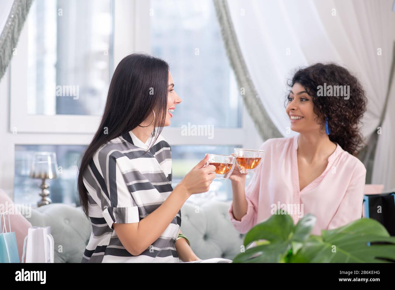 Due donne dai capelli scuri che hanno il tè e parlano Foto Stock