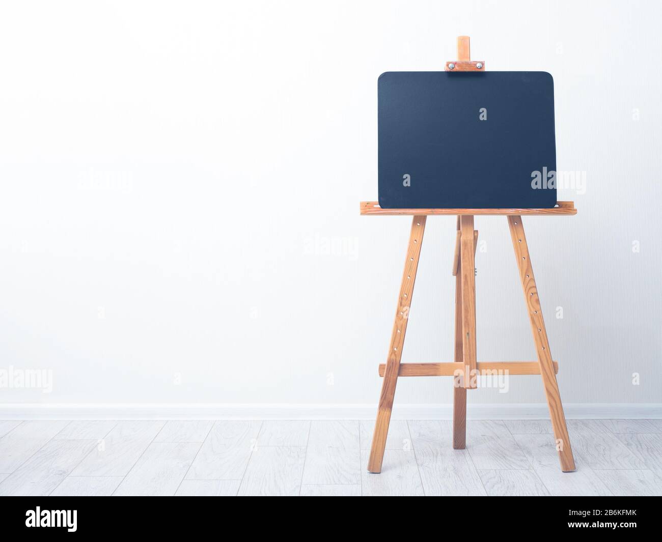 Lavagna bianca, cavalletto in legno, vista frontale, sullo sfondo di una parete bianca. Lavagna Foto Stock