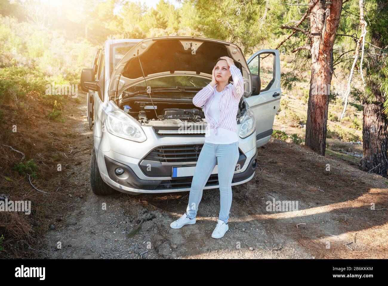 Donna sta aspettando disperatamente con cofano auto aperto per il supporto di risolvere i problemi dell'automobile. Concetto di trasporto e veicolo Foto Stock