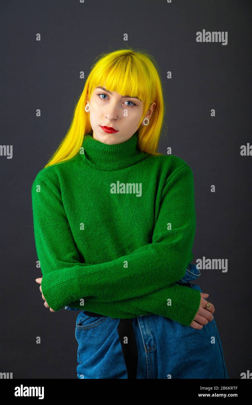 Moda colpo di una giovane donna di colore giallo brillante dei capelli e indossando un colore verde brillante il ponticello contro uno sfondo bianco. Foto Stock