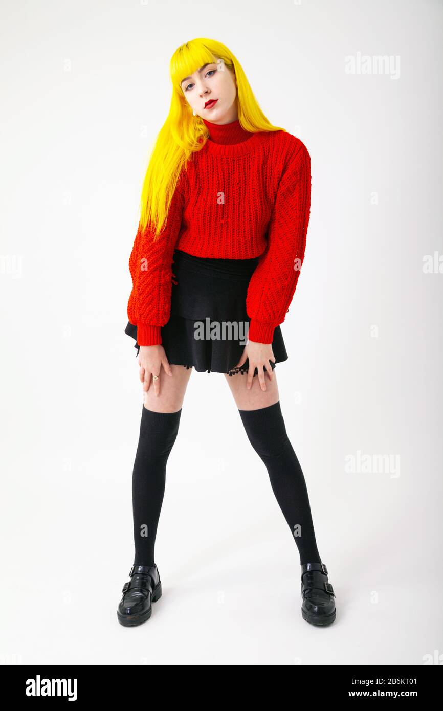 Una giovane donna con colore giallo brillante capelli indossando un top rosso su sfondo bianco Foto Stock