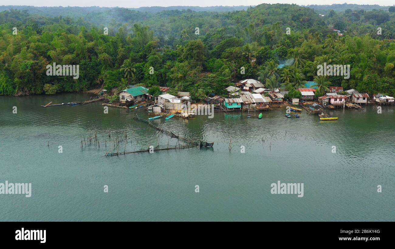 Villaggio di pescatori con barche e baraccopoli con case in legno, drone aereo. Case comunità in piedi in acqua nel villaggio di pescatori. Luzon, Filippine. Foto Stock