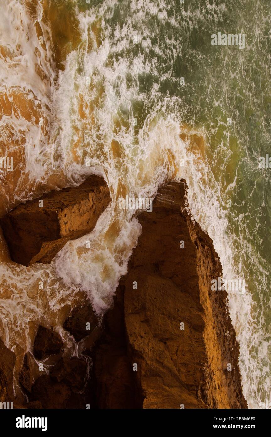 Le onde si infrangono contro le rocce, come si vede dalla cima di una scogliera. Foto Stock