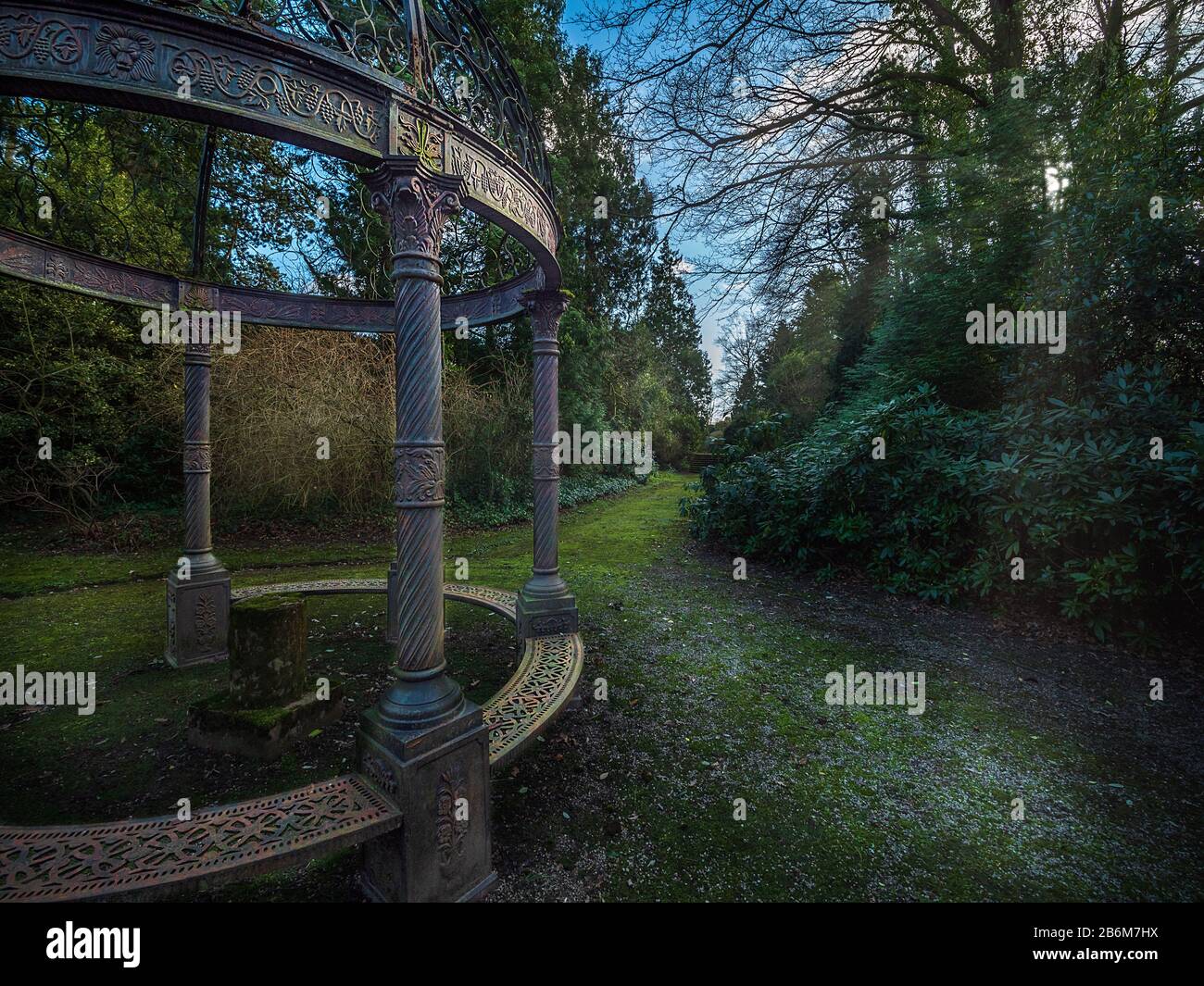 Una panchina circolare in ghisa vittoriana nei terreni di Thornton Manor - ex casa dei Visconte Leverhulme Foto Stock
