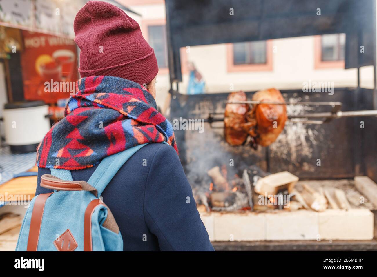 Donna turista guarda la cottura di un ginocchio di maiale su un fuoco aperto all'aperto Foto Stock