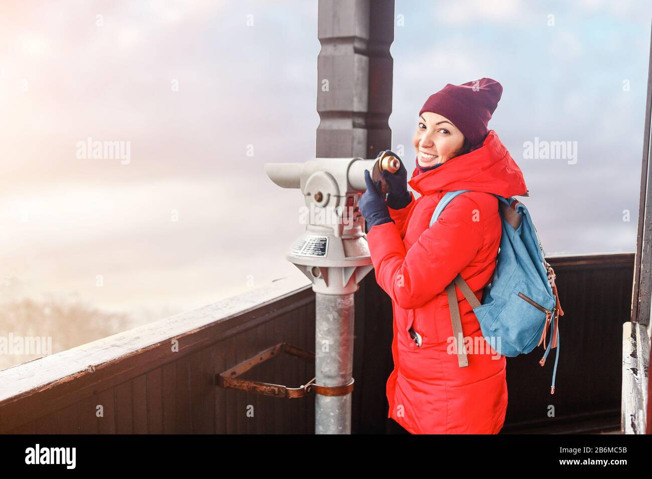 Bella donna che guarda la città attraverso il telescopio turistico in inverno Foto Stock