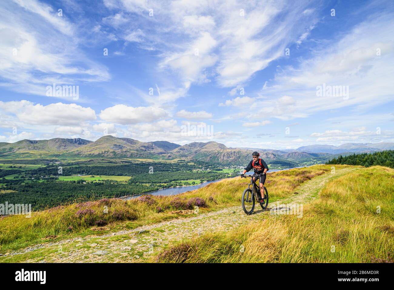 Ciclista (in bicicletta elettrica) sul crinale di Park Crags, con Coniston Water e le Coniston Fells dietro, nel Distretto dei Laghi Inglese Foto Stock