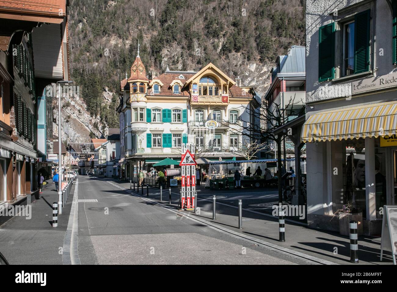 Interlaken città strada scena con boscosa collina oltre Foto Stock