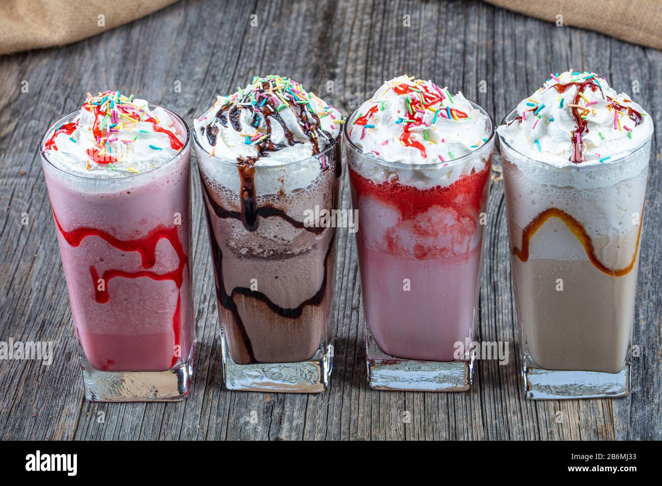 Quattro bicchieri di colorati cocktail milkshake - Milkshake al cioccolato,  Milkshake al fragola, Milkshake al caramello, Milkshake decorato con frutti  di bosco freschi Foto stock - Alamy